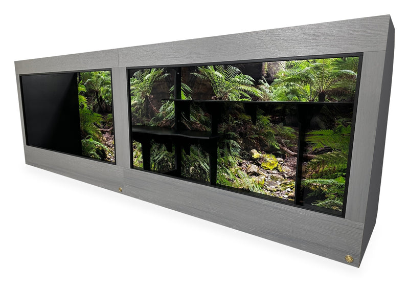 12'x2.5'x4' two-section reptile enclosure with Driftwood gray woodgrain HDPE front frame and black PVC body. Options shown: 10-inch lower frame, Blue Mountains Destinations background and custom shelves.